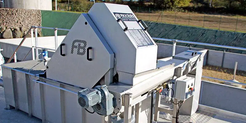 Industrial machinery for waste processing, featuring a large gray metal structure and electric motor on an outdoor platform.