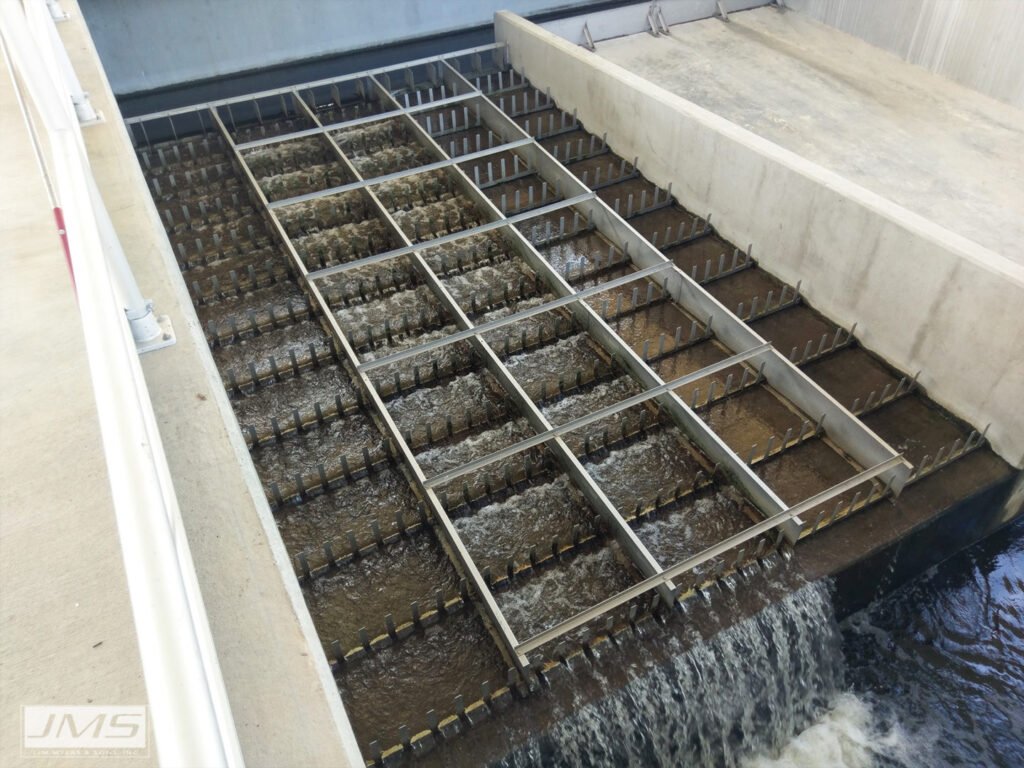 Industrial water filtration system with metal screens and flowing water, viewed from above.