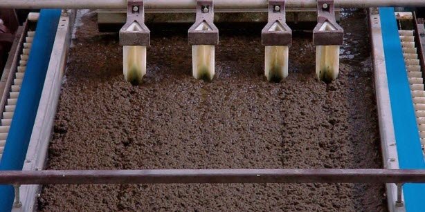 Close-up of a wastewater treatment process with four filtration units removing contaminants from sludge.