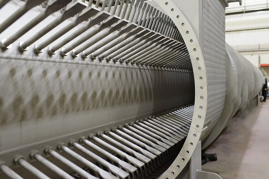 Interior view of a large industrial heat exchanger reveals rows of long metal tubes aligned parallel inside a cylindrical chamber. This perspective showcases the depth and complexity of the machinery within a factory setting, integral to efficient thermal processes.