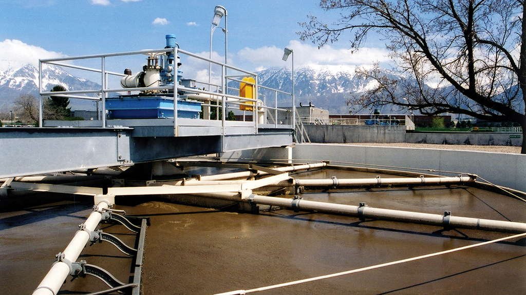 Water treatment facility with circular tanks and snowy mountains in the background.