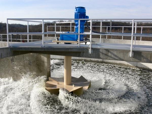 Water treatment facility with large blue motor and turbine agitating water in circular motion.