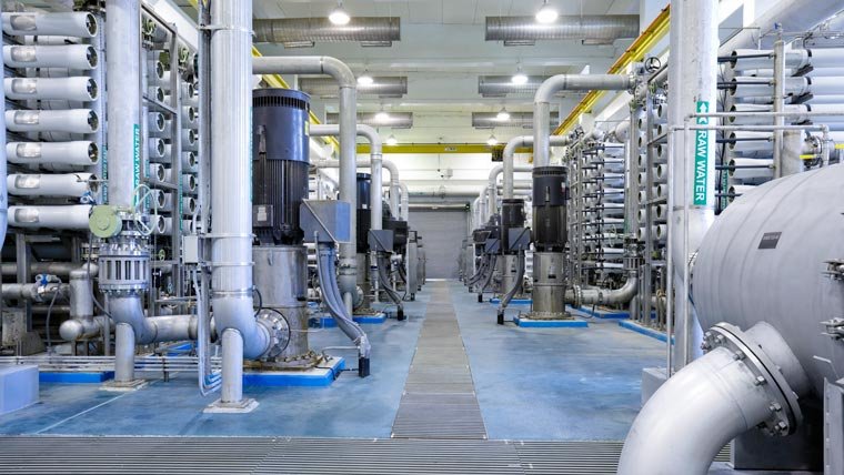 Interior of a modern water treatment plant with rows of large filtration equipment and pipes.