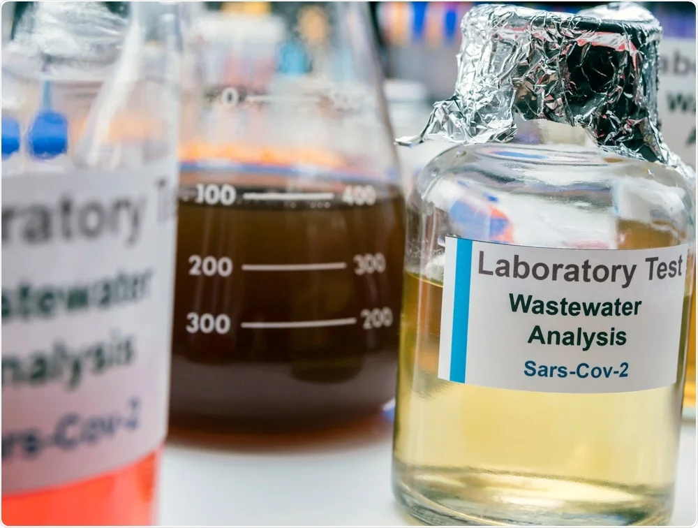 Close-up of labeled laboratory containers, focusing on a clear bottle labeled "Laboratory Test Wastewater Analysis Sars-Cov-2." Surrounding containers with colored liquids highlight ongoing monitoring and sampling for compliance and efficiency in scientific analysis.