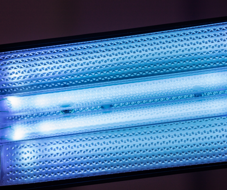 Close-up of a fluorescent light fixture with a textured, metallic surface and blue-toned illumination. The light emits a bright, cool glow, highlighting the intricate pattern on the fixture's interior.